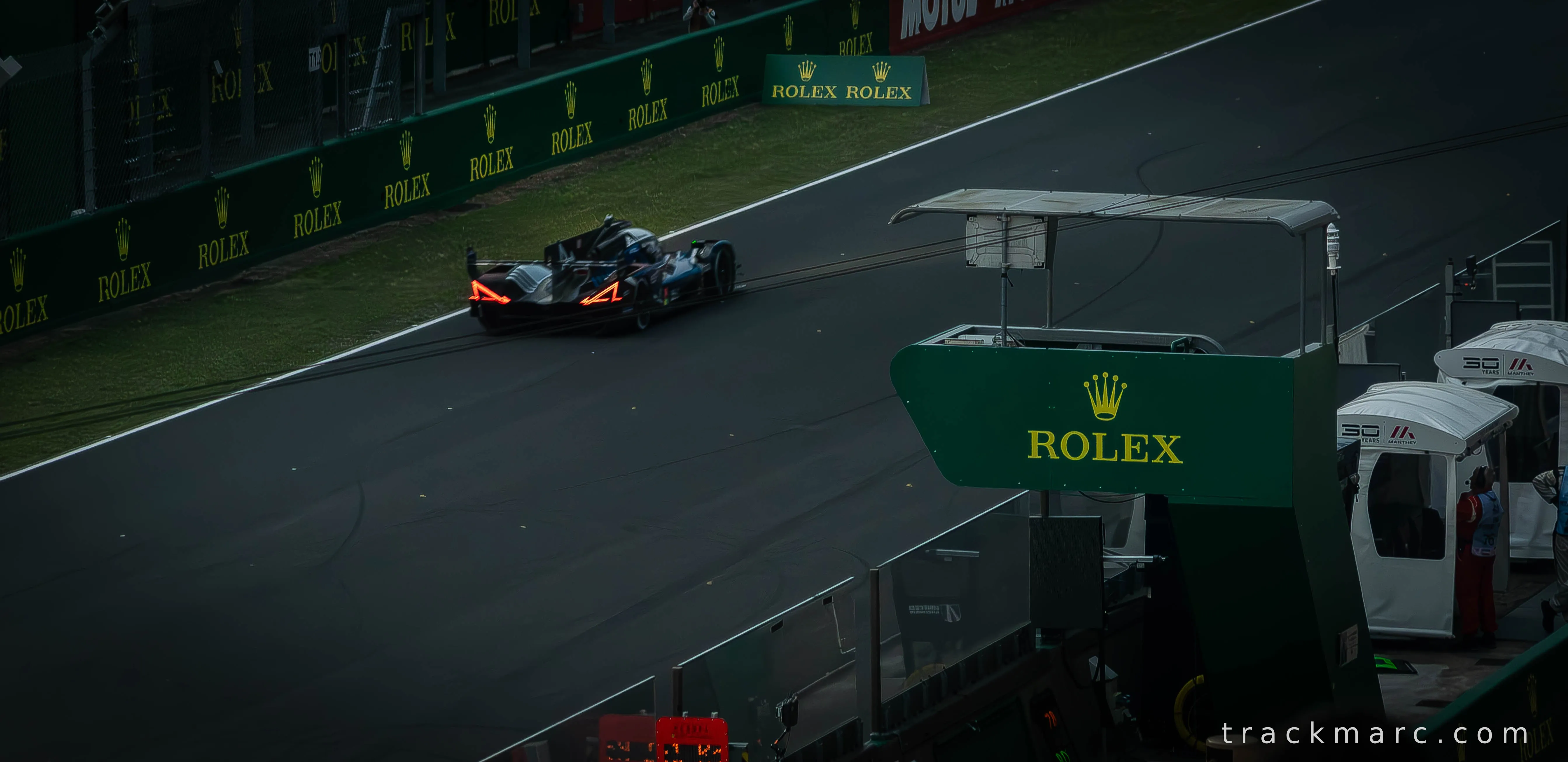 Hypercar Passes the Pit Lane at Dusk